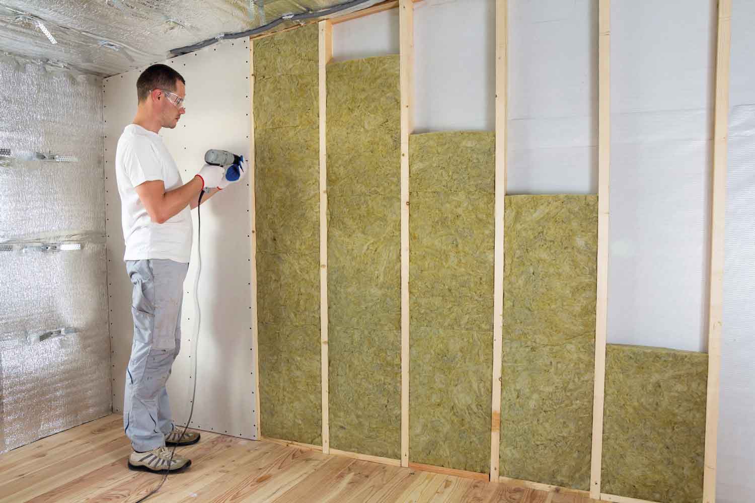 Man fitting insulation into a home